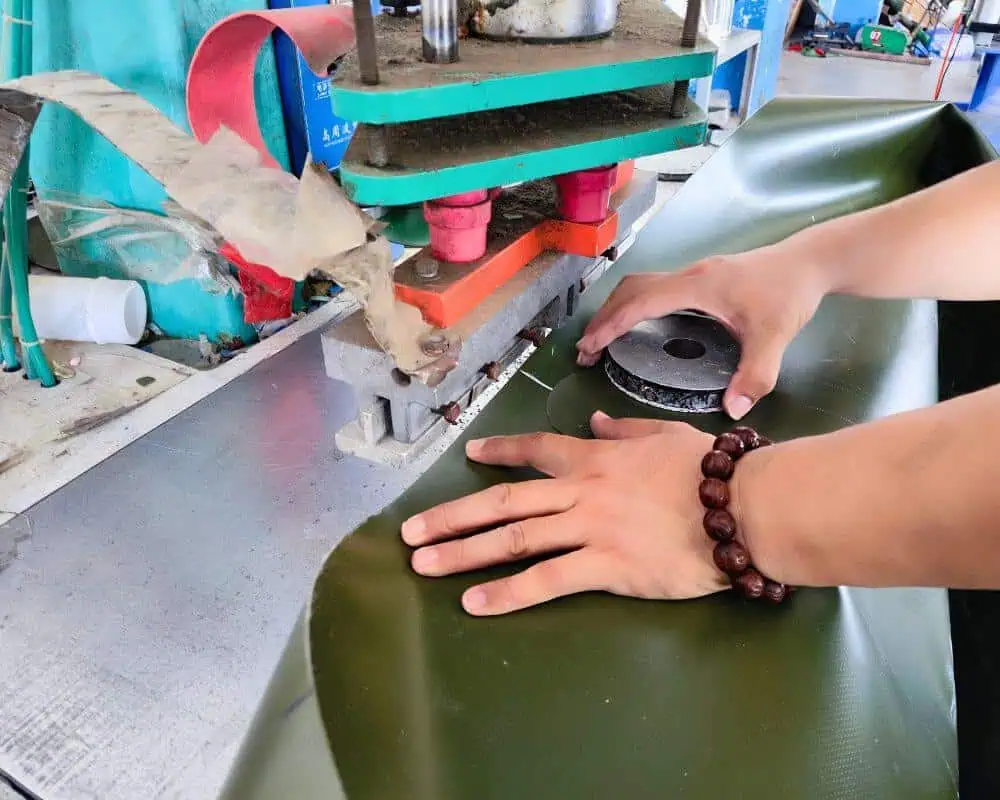 Operator using a heat sealing machine to join materials for tank assembly
