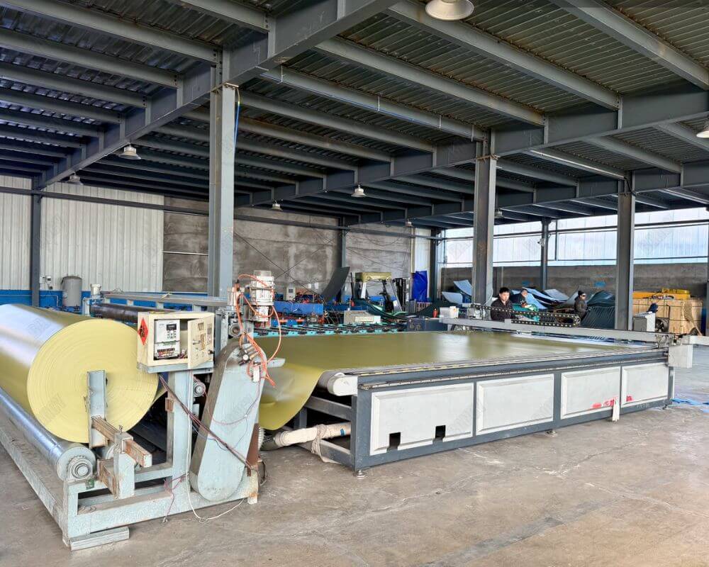 Large fabric cutting machine preparing materials for tanks in a spacious workshop
