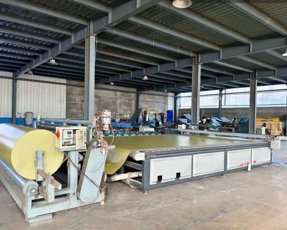 Large fabric cutting machine preparing materials for tanks in a spacious workshop