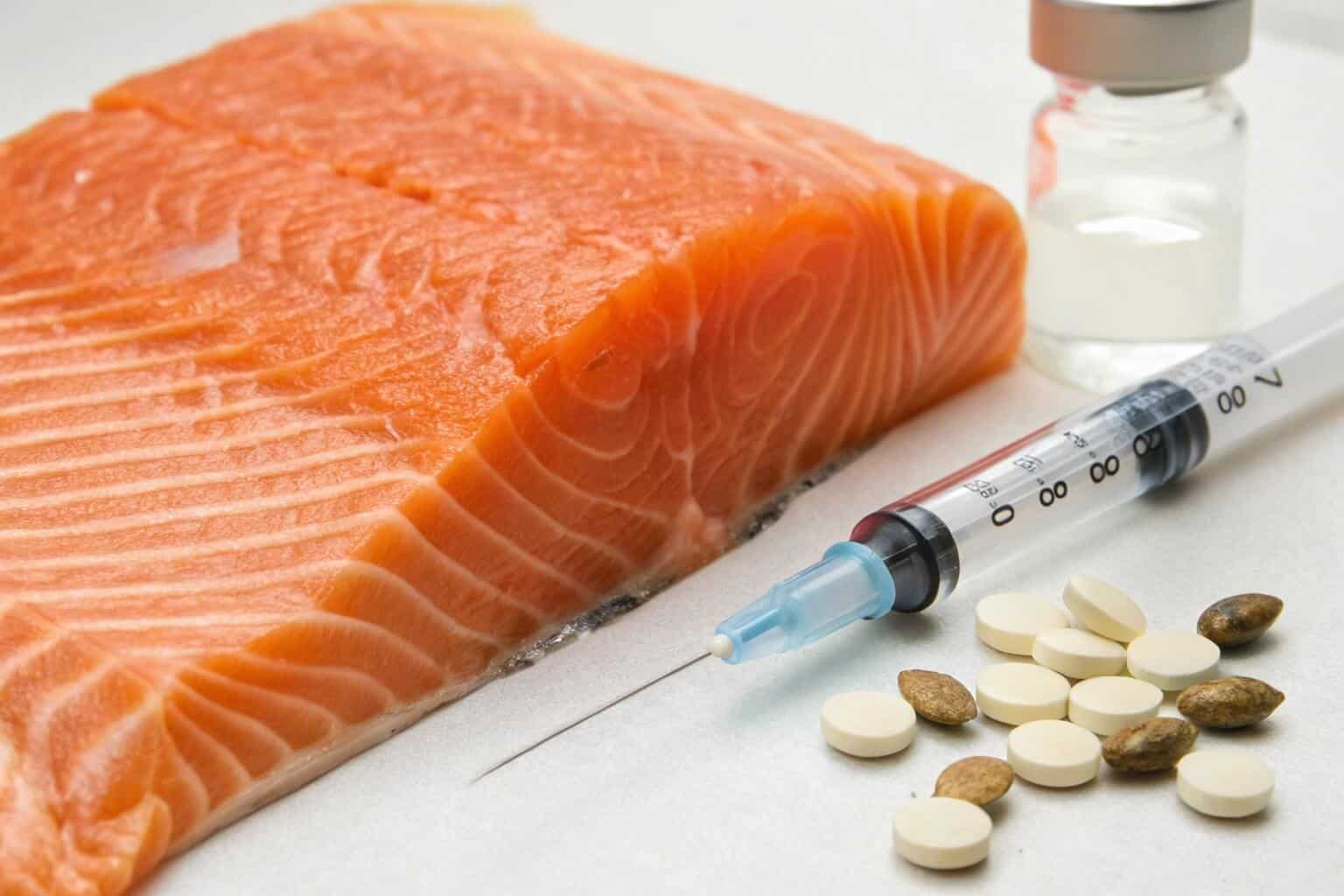 A close-up shot of pills and a syringe next to a farmed salmon.