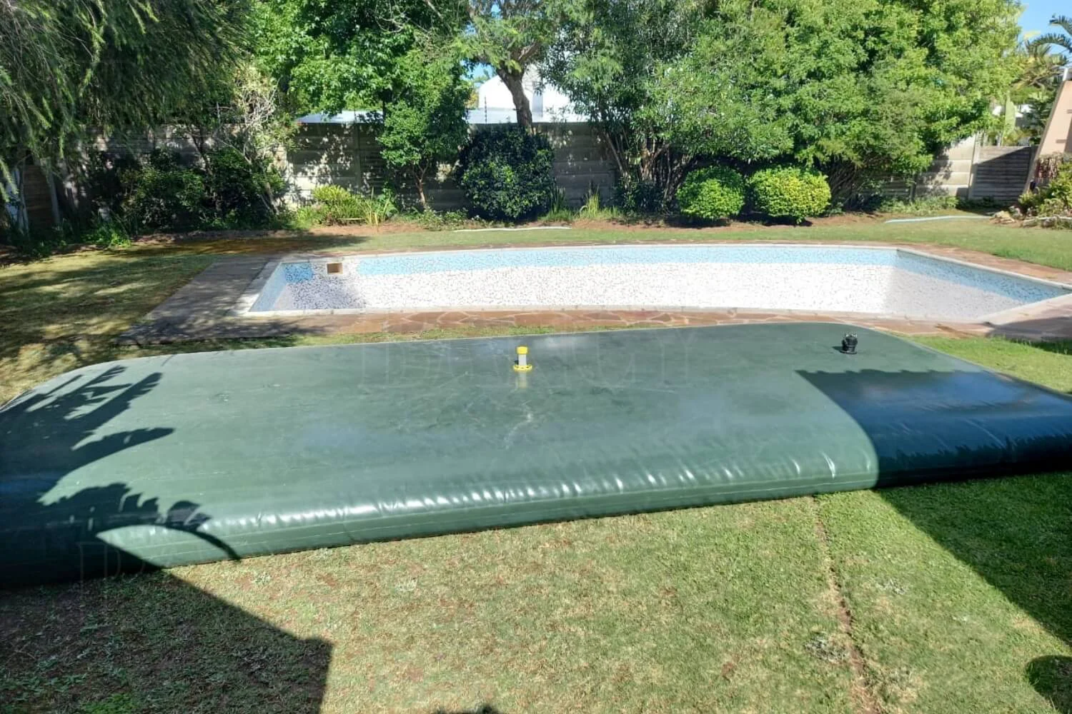 Green custom flexible tank deployed on a lawn for swimming pool water storage, matching the layout sketch.