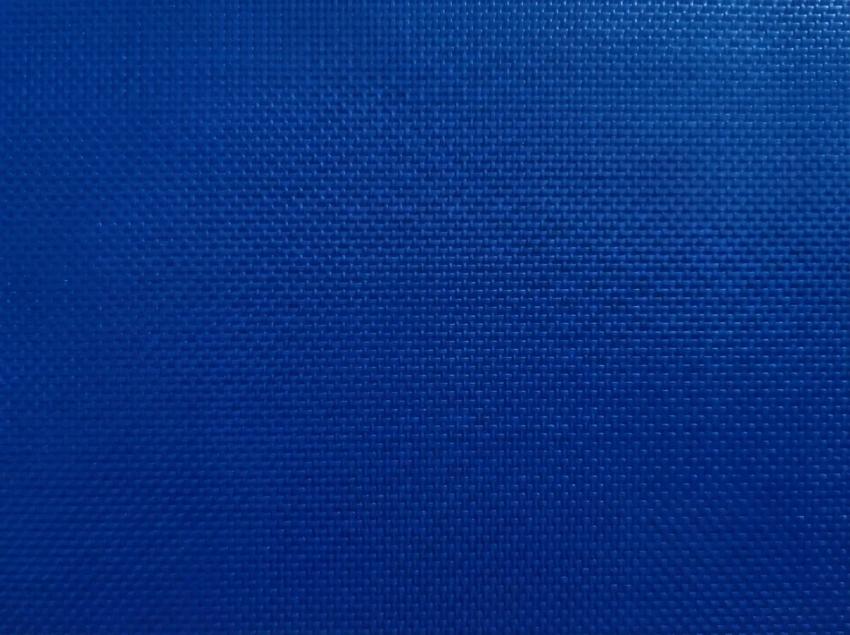 Macro shot of blue PVC tarpaulin texture showing embedded high-density mesh reinforcement.