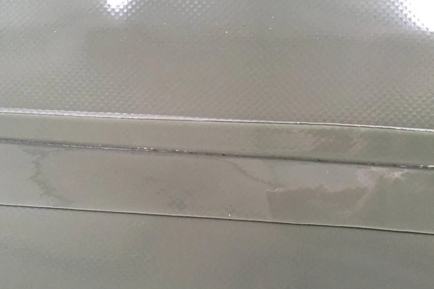 Heat sealing machine creating reinforced seams on grey PVC material