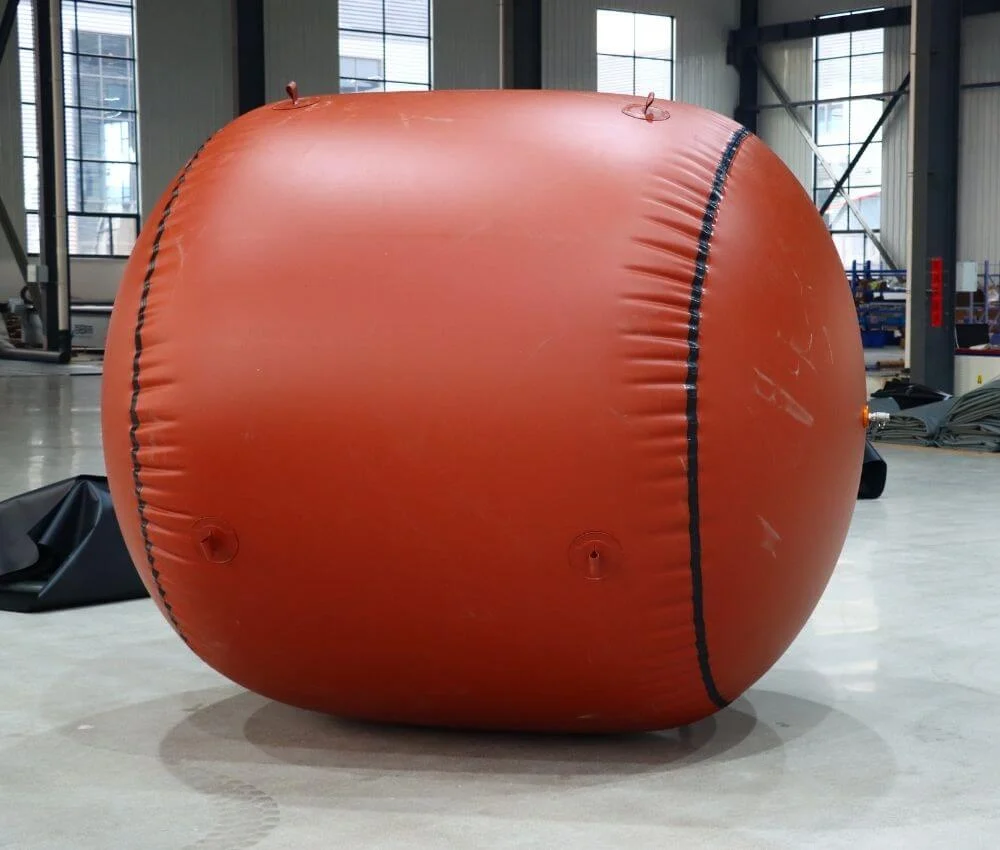 Side view of a fully inflated cylindrical red mud biogas balloon showing the black double-layer reinforced welded seam.